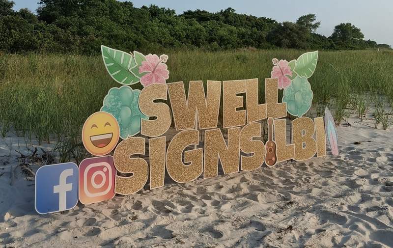 A Swell Signs & Celebrations yard card display set up on the beach at Long Beach Island, New Jersey